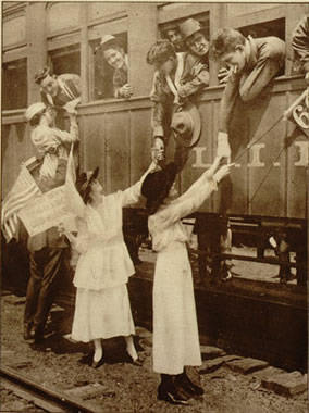 Women holding hands outside a train with soldiers who are hanging out of the train windows, saying goodbye