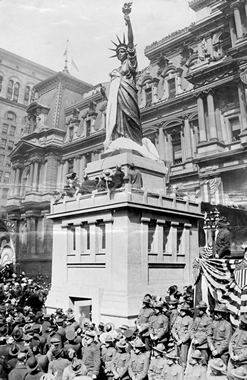 a crowd gathered around a replica of the Statue of Liberty