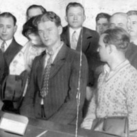 men and women lined up in a court room, some of them hiding their faces from the camera with their hands